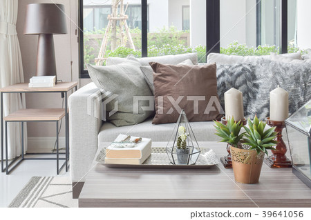 Brown pillows on beige sofa with candles on table 39641056
