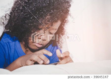 Little kid is playing with smartphone on bed Little kid is playing with smartphone on bed 39645147