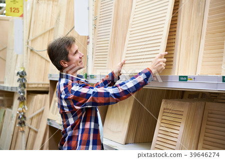 Man chooses wooden facades for furniture in store Man chooses wooden facades for furniture in store 39646274