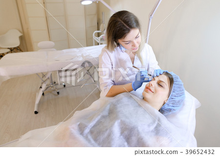 Qualified cosmetologist making makeup by eyebrow 39652432