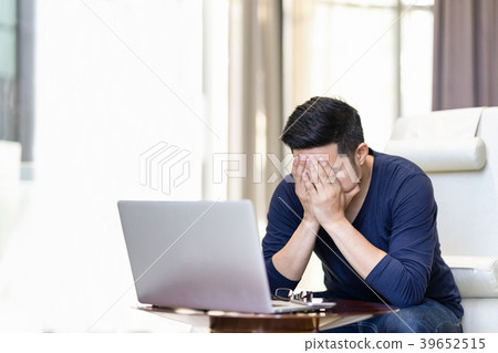 Stressed out asian man holding hand on his face.  39652515