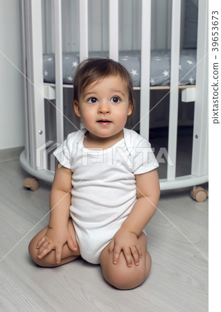 child in white clothing one year sitting on the 39653673