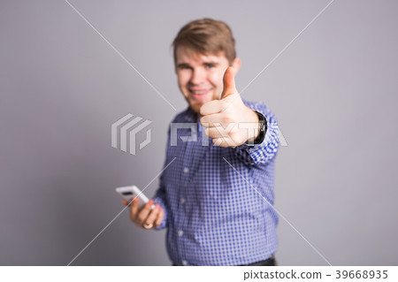Young optimistic man with cell phone on gray 39668935