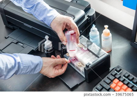 Man pours red ink into the photo printer container Man pours red ink into the photo printer container 39675065