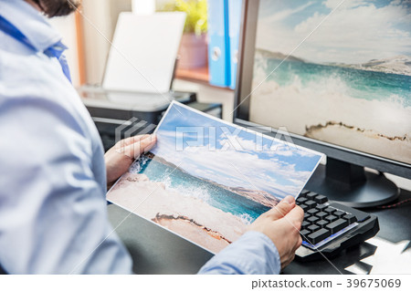 The graphic designer compares the printed photo The graphic designer compares the printed photo 39675069