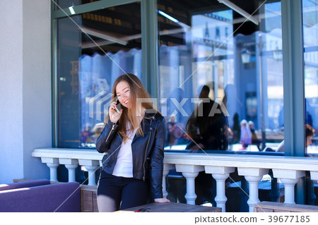 Young person talking by smartphone at street cafe. 39677185