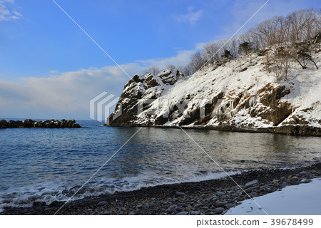 The cape covered with white snow shines in the blue sky, and the water surface quietly hits the shore without waves. The cape covered with white snow shines in the blue sky, and the water surface quietly hits the shore without waves. 39678499