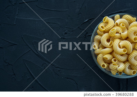 rigati Pasta in a glass cup on a black textured rigati Pasta in a glass cup on a black textured 39680288