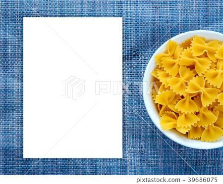 farfalle macaroni pasta in a white bowl on a blue farfalle macaroni pasta in a white bowl on a blue 39686075