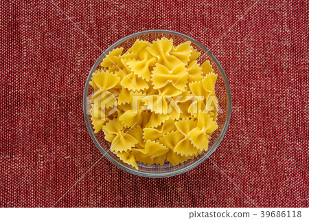 farfalle macaroni pasta in a glass bowl on a red farfalle macaroni pasta in a glass bowl on a red 39686118