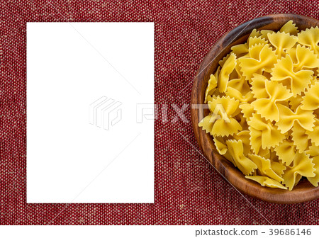 farfalle macaroni pasta in a wooden bowl on a red farfalle macaroni pasta in a wooden bowl on a red 39686146