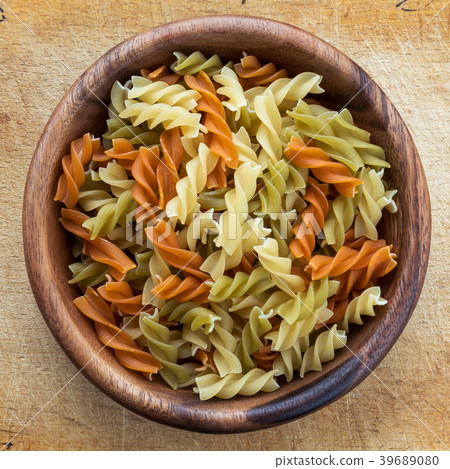 Multicolor spiral macaroni pasta in a wooden bowl 39689080