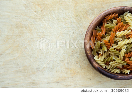Multicolor spiral macaroni pasta in a wooden bowl 39689083