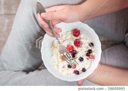 The girl is holding a plate of cottage cheese 39689993