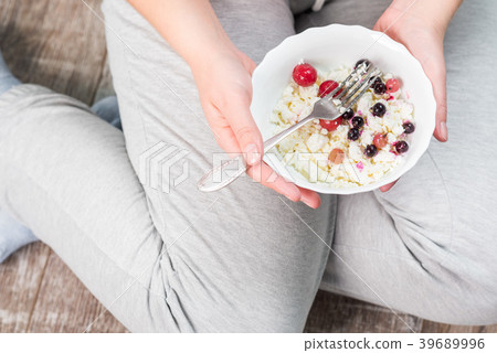 The girl is holding a plate of cottage cheese 39689996