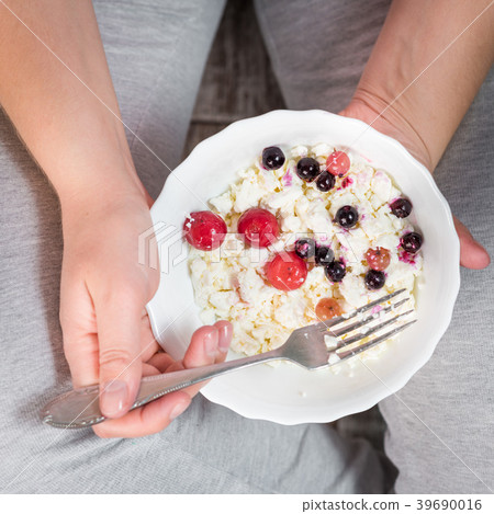 The girl is holding a plate of cottage cheese 39690016
