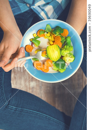The girl holds a plate with vegetables 39690049