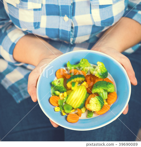 The girl holds a plate with vegetables 39690089