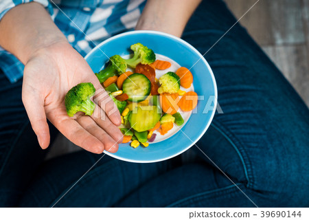 Girl with a plate of vegetables in hands 39690144