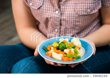 Girl with a plate of vegetables in hands 39690184