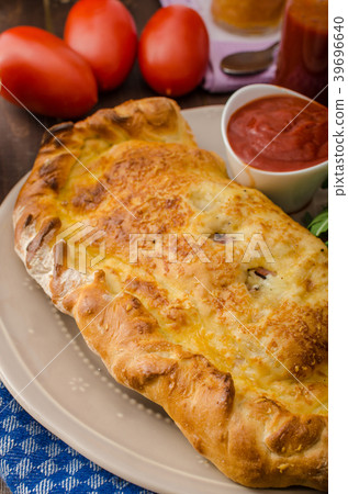 Calzone pizza stuffed with cheese and prosciutto 39696640