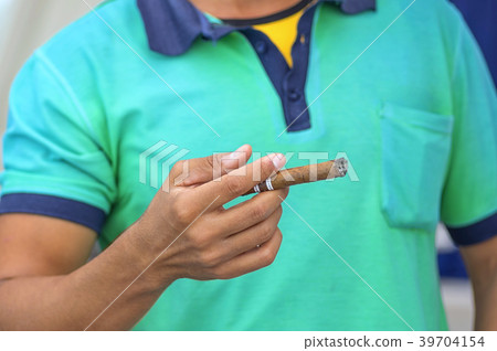 Cuban cigar in a man's hand against a light shirt 39704154