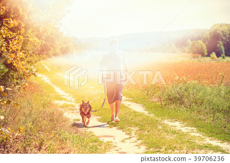 A man with a dog walks along the dirt road A man with a dog walks along the dirt road 39706236