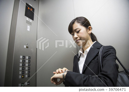 Business woman looking at clock in elevator Business woman looking at clock in elevator 39706471
