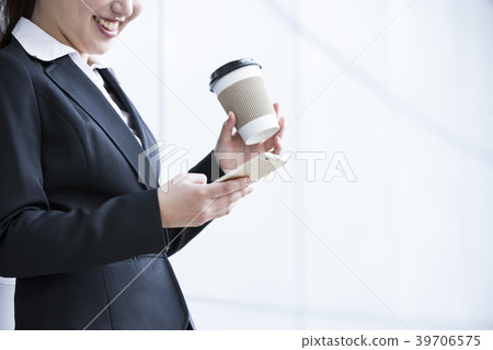 Business woman looking at smartphone while drinking hot drink Business woman looking at smartphone while drinking hot drink 39706575