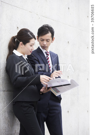 Upper body of businessman and businesswoman looking at materials 39706685