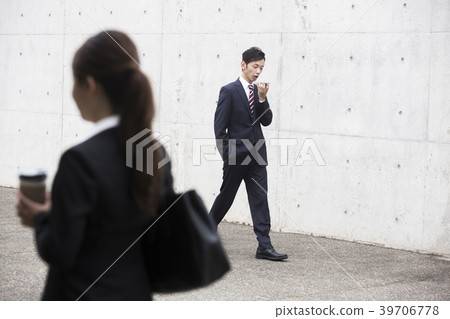 Woman passing by businessman talking to smartphone 39706778