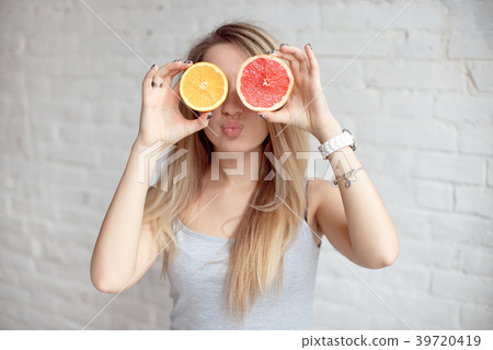 Happy smiling Woman holding two halves of citrus Happy smiling Woman holding two halves of citrus 39720419
