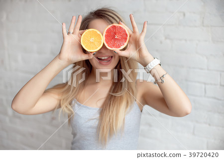 Happy smiling Woman holding two halves of citrus Happy smiling Woman holding two halves of citrus 39720420