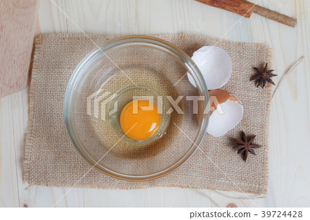 Egg on clear glass bowl over wooden cut 39724428