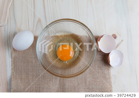 Egg on clear glass bowl over wooden cut board  39724429