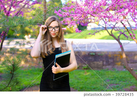 Female student touching glasses in garden and Female student touching glasses in garden and 39728435