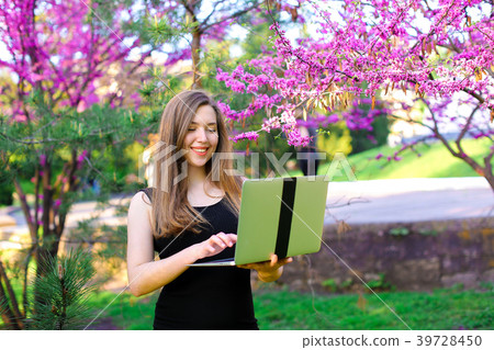 Pretty female person using laptop in blooming 39728450