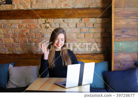 Woman making video call by laptop at cafe and 39728677
