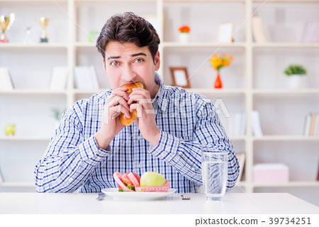 Man having dilemma between healthy food and bread 39734251