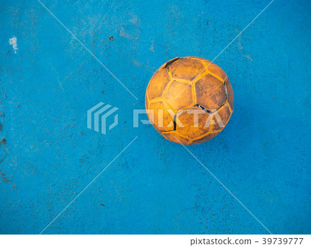 Old yellow soccer ball on the blue football field. 39739777