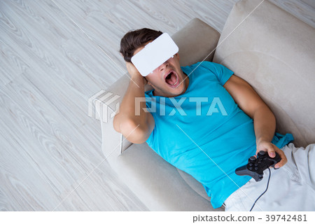 Young man wearing VR glasses relaxing on couch Young man wearing VR glasses relaxing on couch 39742481