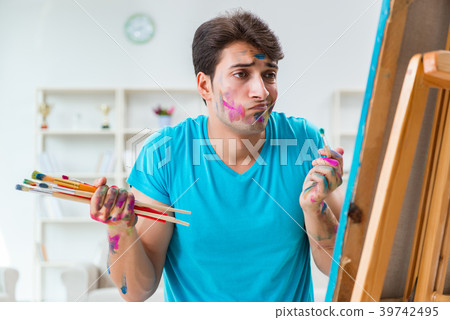 Young funny artist working on new painting in his Young funny artist working on new painting in his 39742495