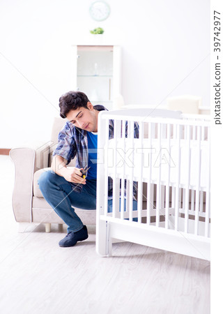Young man assembling baby bed with instruction 39742977