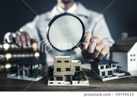 Male in working clothes peeking a house model with a loupe Male in working clothes peeking a house model with a loupe 39744019
