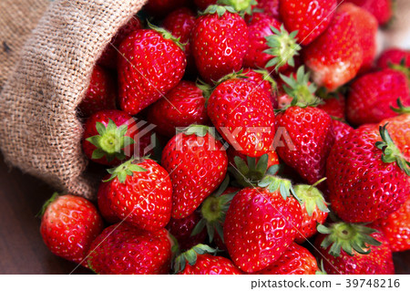 Many fresh strawberries overflowing from a hemp bag Many fresh strawberries overflowing from a hemp bag 39748216