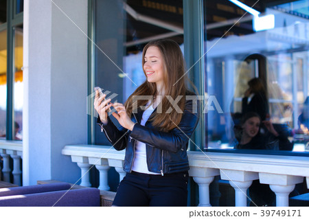 Young lady typing by smartphone at street cafe. Young lady typing by smartphone at street cafe. 39749171