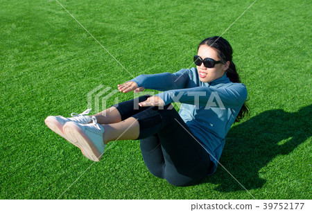 Girl doing situps on the grass, outdoor workout 39752177
