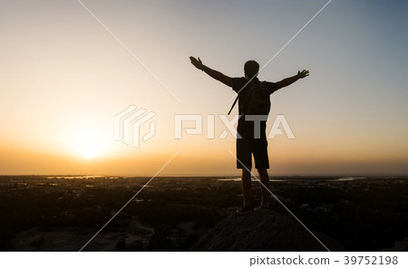 Hiker on the mountain top facing the sunset 39752198