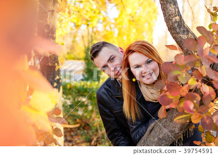 Young couple peeking from behind tree 39754591