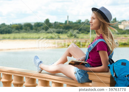 Pretty student sitting with a book near the river. 39763778